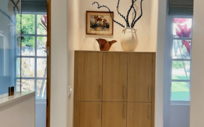 Tall hallway cabinet with warm wood tones, framed by natural light and decorative overhead lighting.