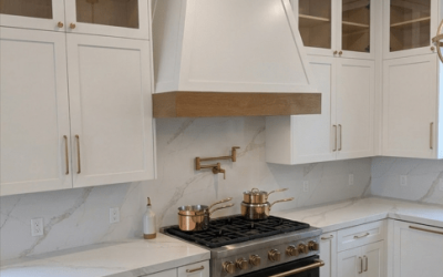 Classic white kitchen with a range hood, marble countertops, and a balanced, symmetrical cabinet layout.