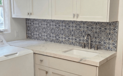 Modern laundry room with white cabinetry, a functional countertop, and a clean tile backsplash.
